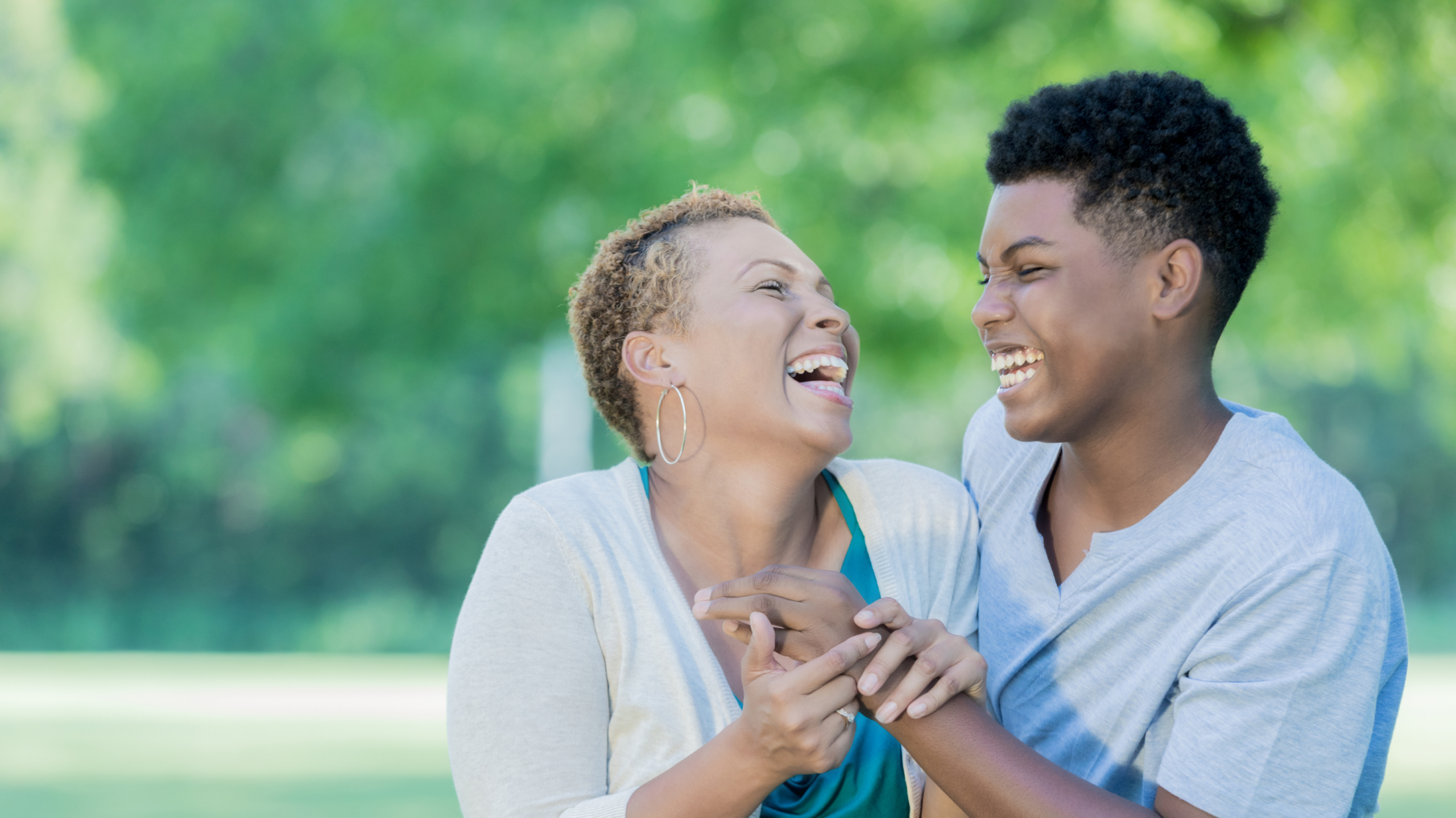 In this photograph, a mom and her teenage son laugh together.